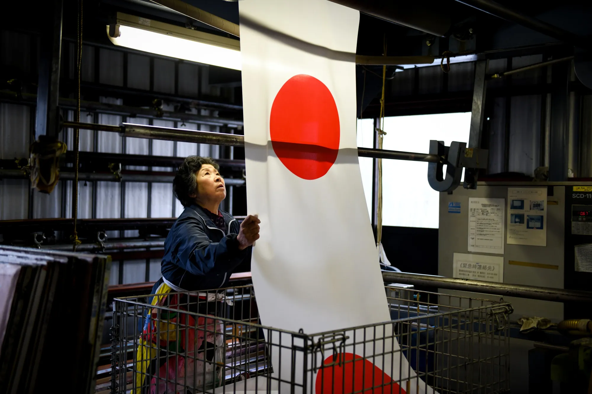 An employee handles Japanese national flags at Tokyo Seiki's manufacturing facility in Numata, Gunma Prefecture.