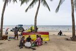 Visitors sit in front of a sign outlining social distancing at Bangsaen Beach in Chonburi, Thailand.