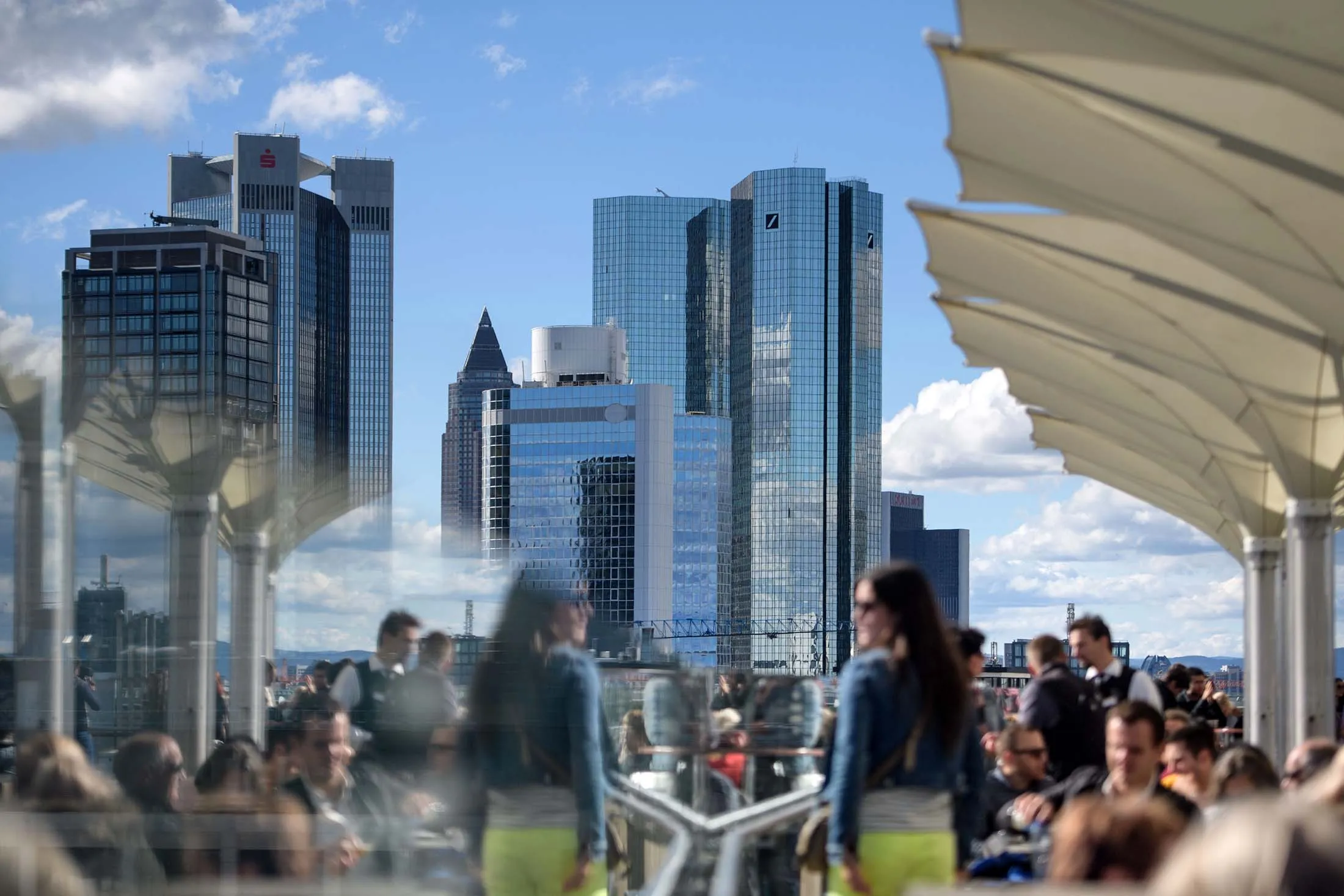 People sit at restaurant roof terrace with the skyline and finance district of Frankfurt