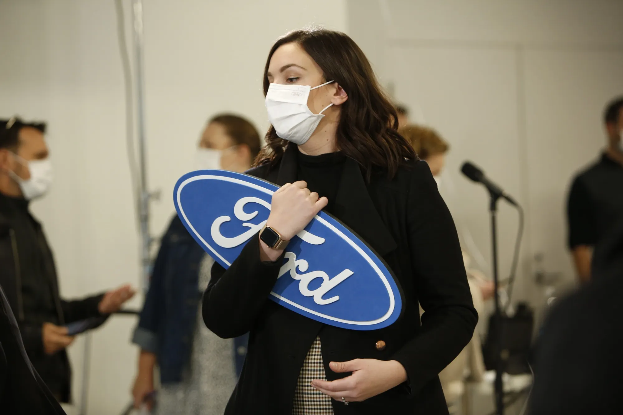 A worker wearing a protective mask holds a Ford sign before a news conference at the Ford Connectivity and Innovation Centre in Ottawa, Canada, in October.&nbsp;
