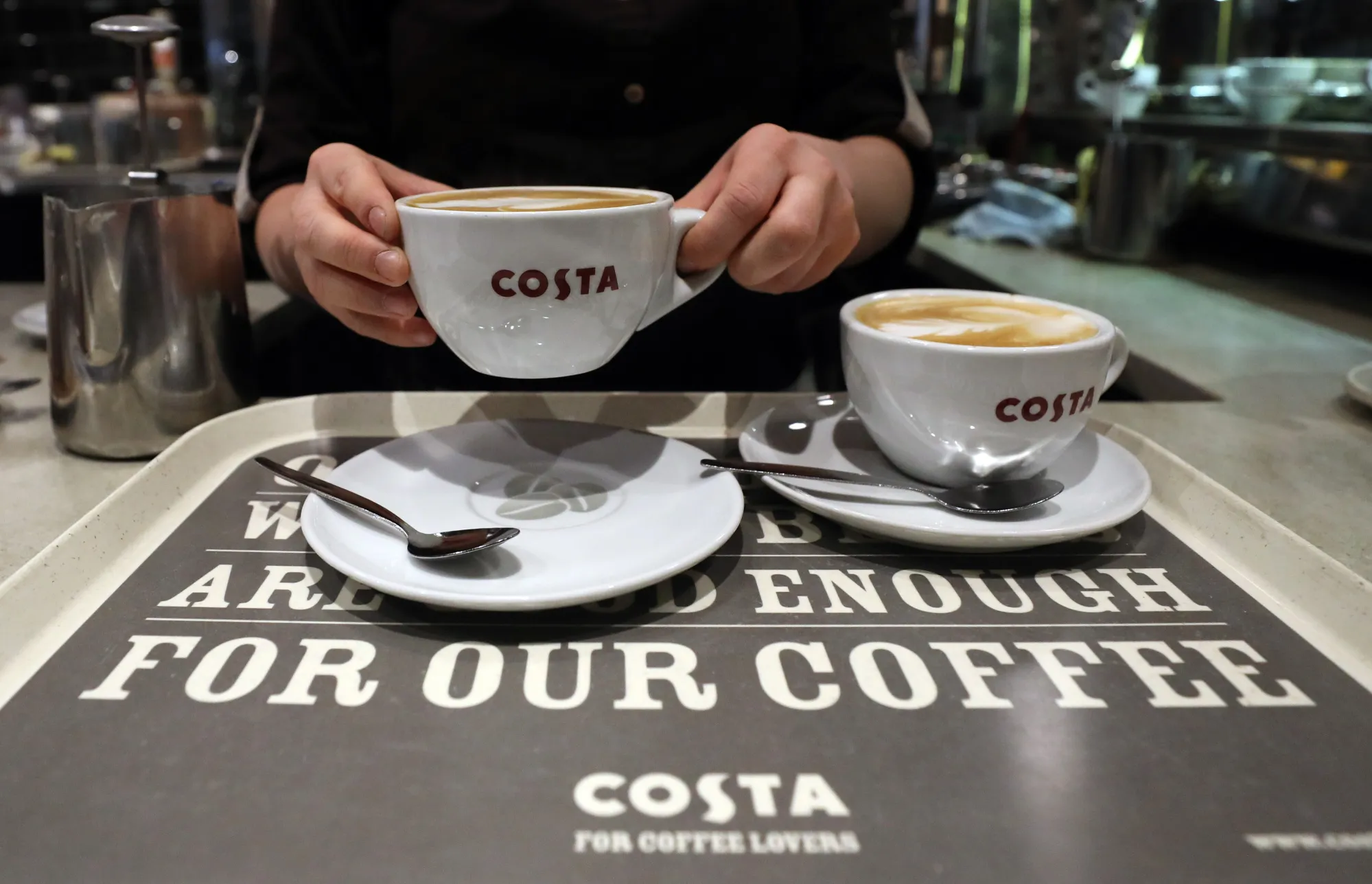 A barista places a coffee on to a serving tray in a Costa Coffee shop in London, UK.