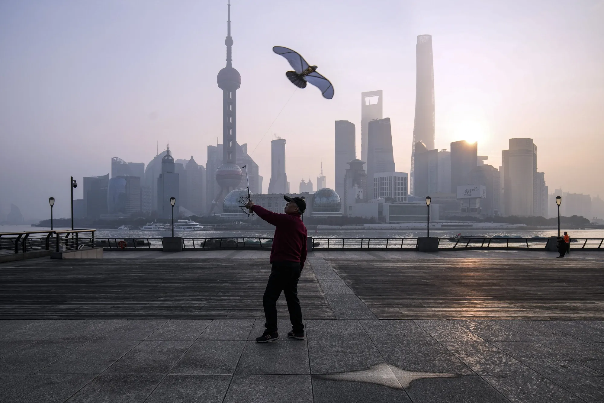 A person flies a kite in front of buildings in Pudong's Lujiazui Financial District in Shanghai, China.