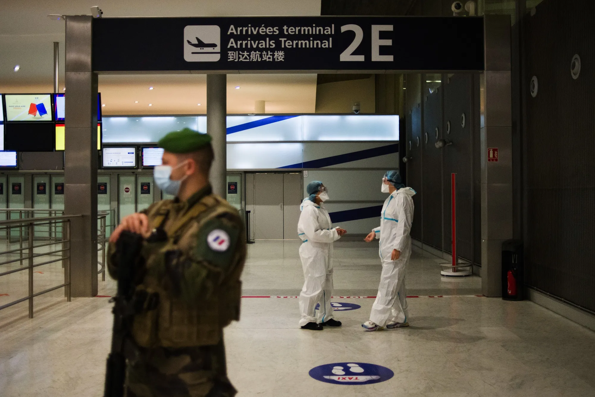 A soldier stands guard near health workers at the Covid-19 test center in the arrival hall at Charles de Gaulle airport, in Roissy, France.