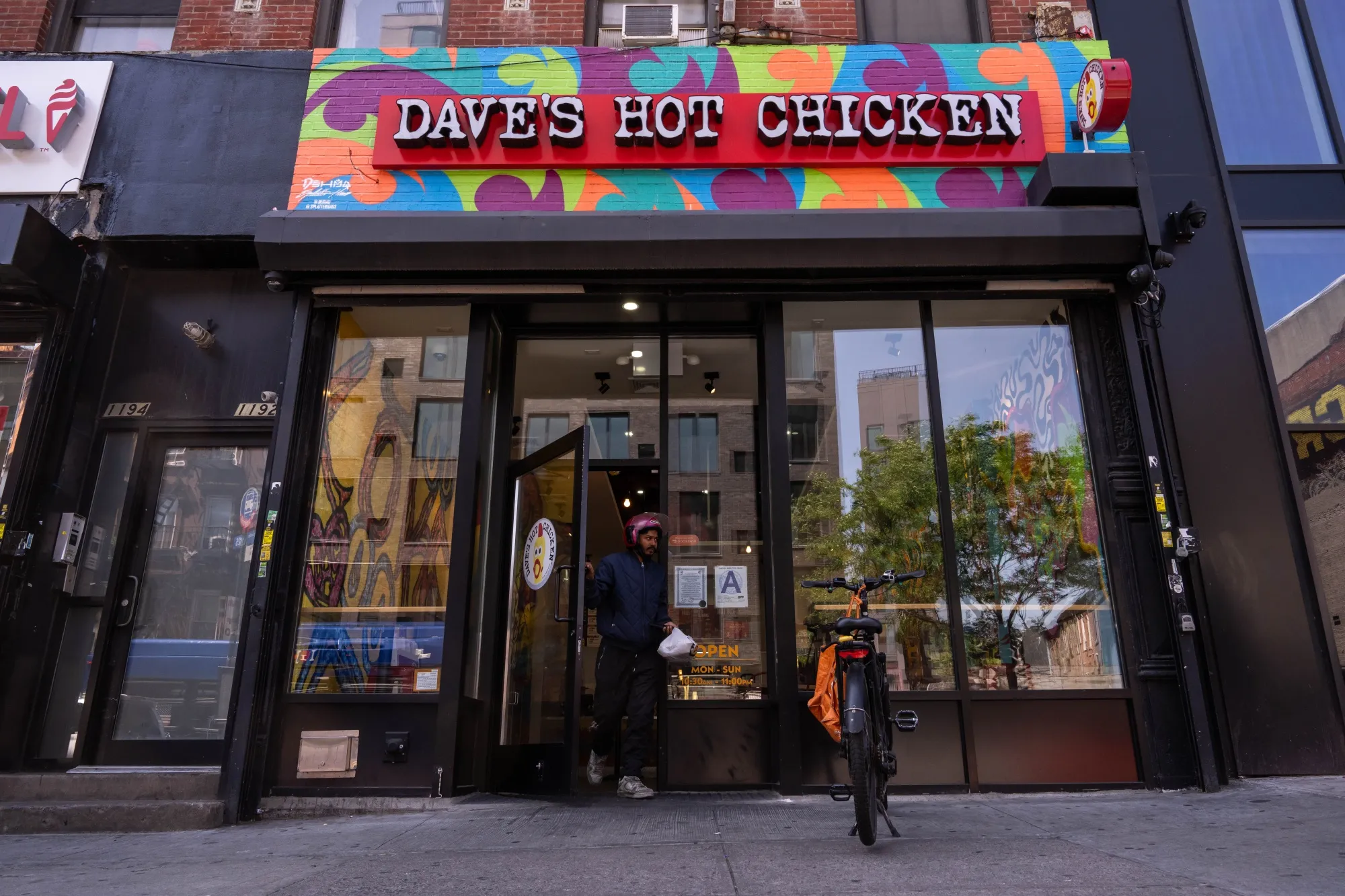 A delivery worker walks out of a Dave's Hot Chicken restaurant in New York.