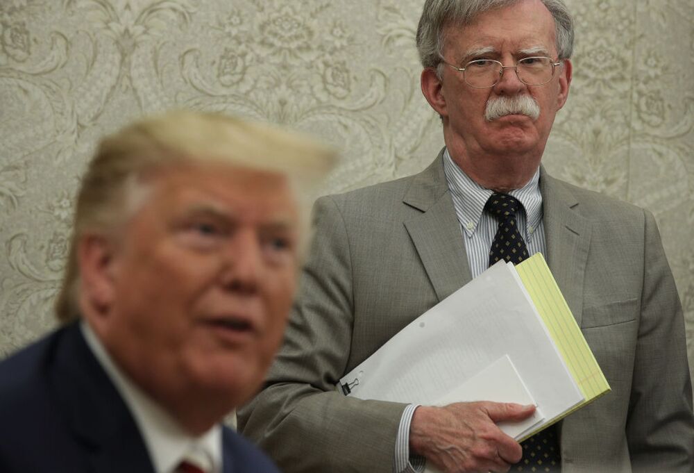  U.S. President Donald Trump speaks to members of the media as National Security Adviser John Bolton listens.