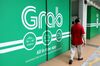 A pedestrian walks past signage for Grab in Singapore.