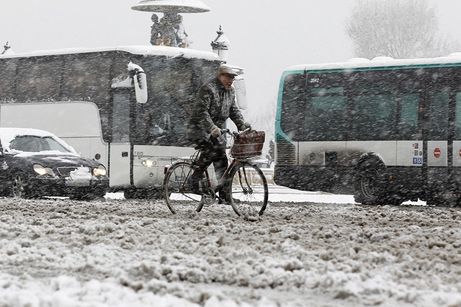 A man cycles in the snow to cross Place de la Concorde in Paris.