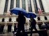 Pedestrians carrying umbrellas pass in front of the New York Stock Exchange (NYSE) in New York, U.S., on Thursday, March 29, 2018. U.S. stocks climbed as markets moved toward the end of a tumultuous quarter on a high note. Equities in Europe also rose following a mixed session in Asia.