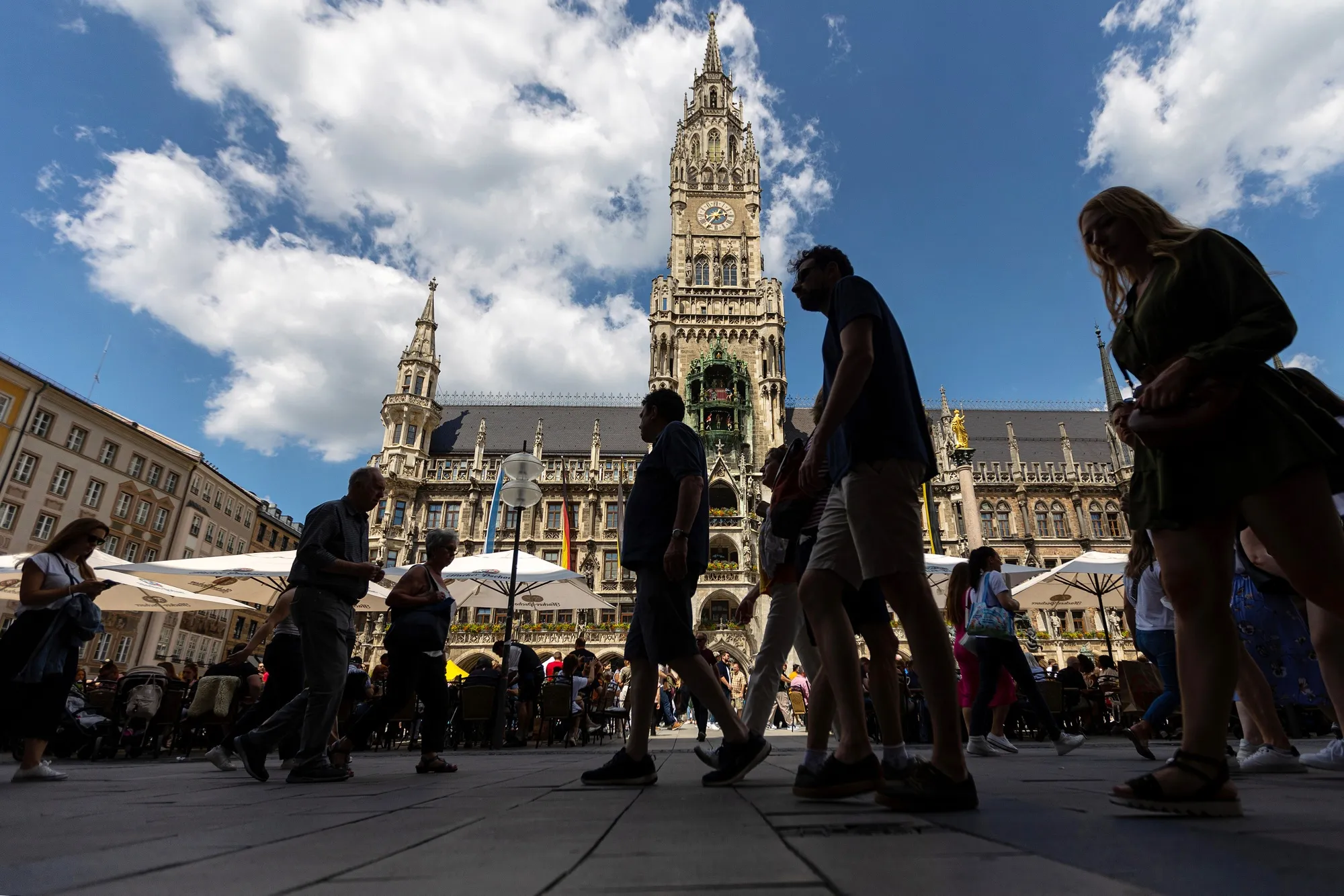 Pedestrians pass customers at a beerhaus terrace at Marienplatz square in Munich, Germany.