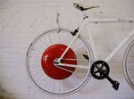 A bicycle fitted with a prototype of the Copenhagen Wheel, the red disk, human/electric hybrid bicycle engine, hangs on a wall at the Superpedestrian manufacturer in Cambridge, Massachusetts.