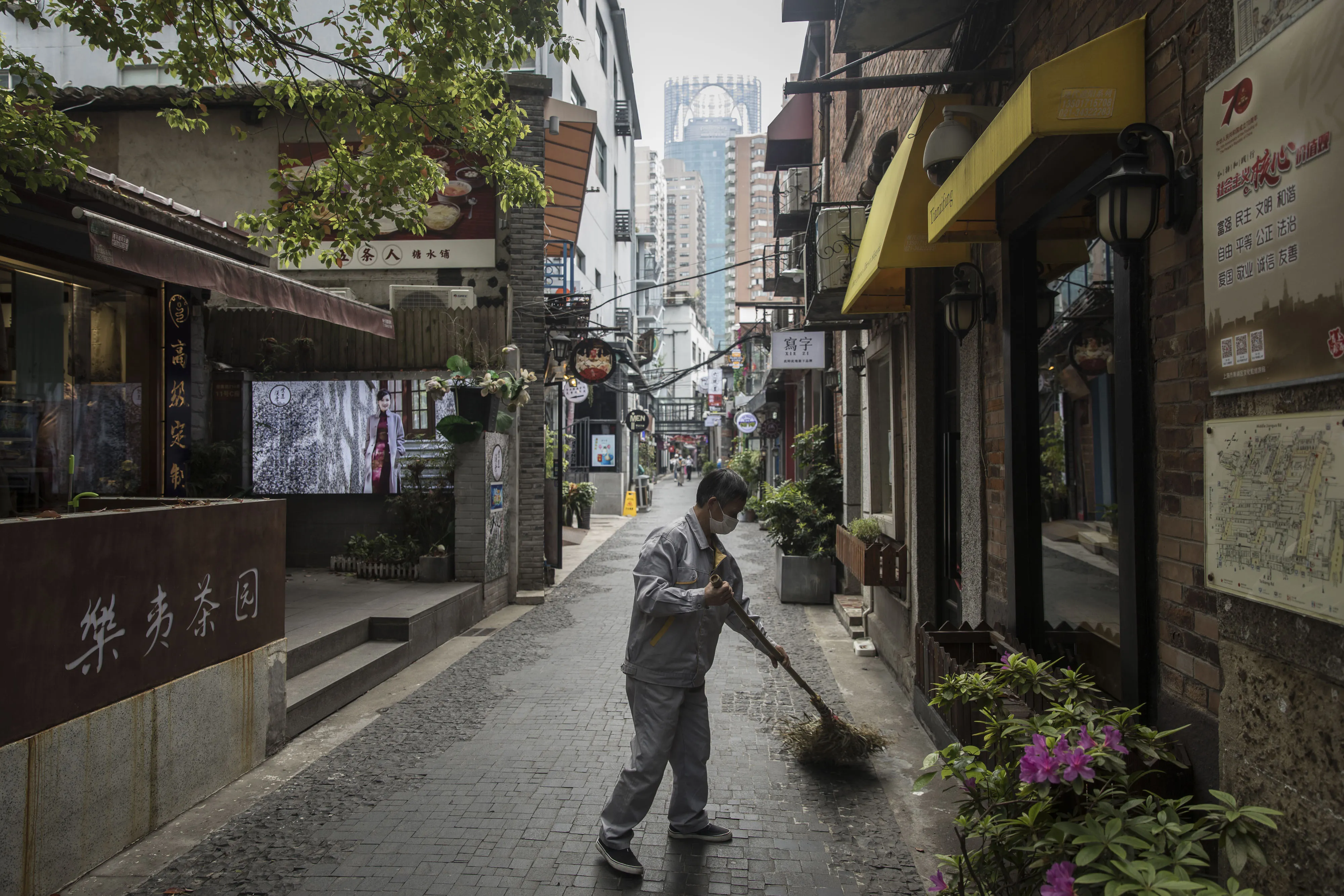 A man wearing a protective mask sweeps a lane in front of stores in the Tianzifang retail precinct in Shanghai, China, on&nbsp;April 20, 2020.&nbsp;