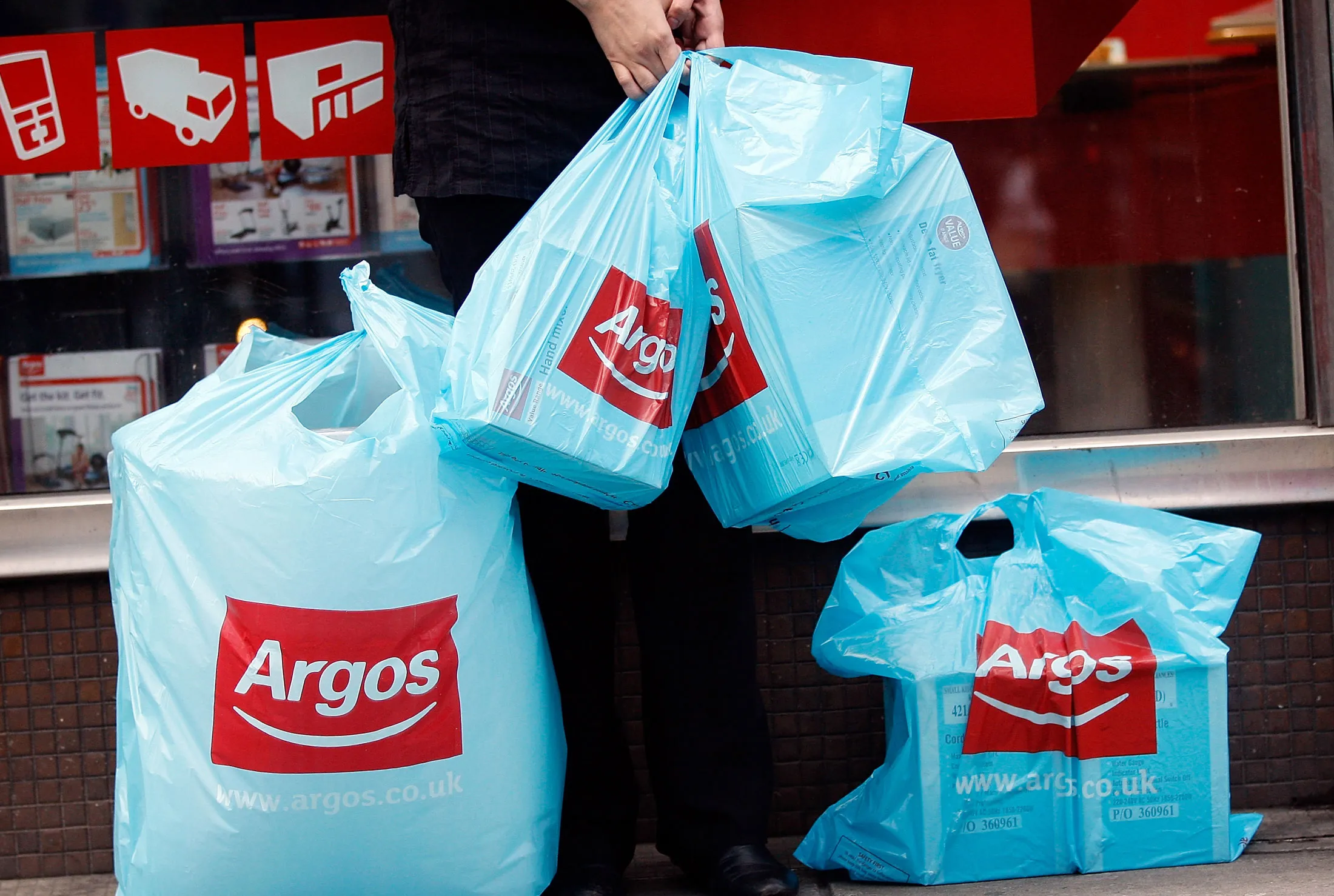 A customer holds branded shopping bags outside an Argos store, operated by Home Retail Group Plc, in London U.K., on Tuesday, Jan. 11, 2010. U.K. retail sales fell last month as snow and the coldest December temperatures in at least a century deterred shoppers, the British Retail Consortium said.
