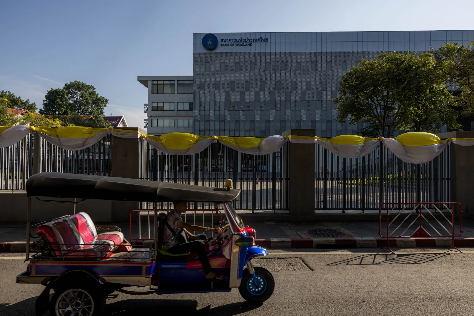 A tuktuk drives past the Bank of Thailand complex in Bangkok.
