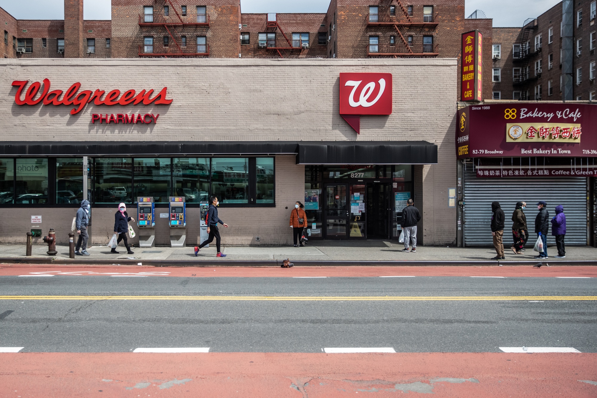 People wearing protective masks wait in line to get into a Walgreens Boots Alliance Inc. store in Queens, New York, in April.