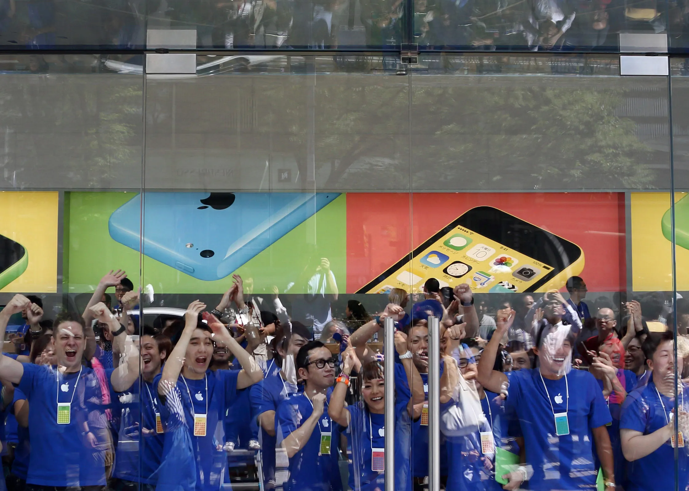 Employees cheer and applaud before the opening of the Apple Inc. Omotesando store in Tokyo, Japan, on Friday, June 13, 2014.
