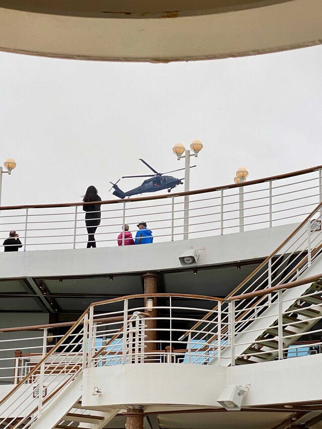 A helicopter flies over the <em>Grand Princess</em> preparing to drop supplies.