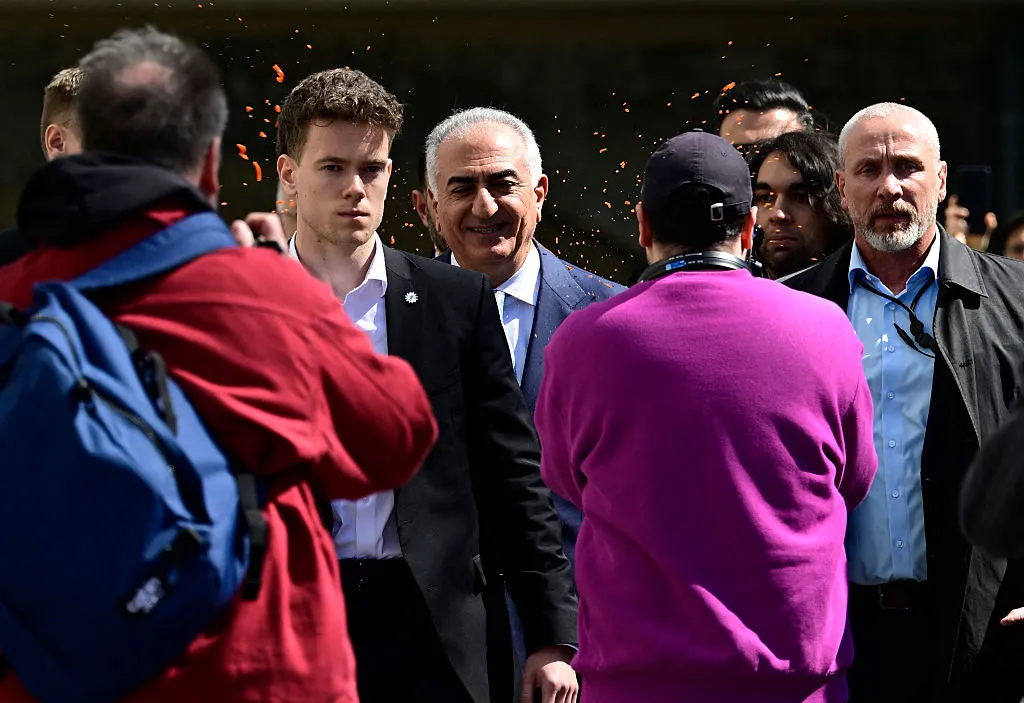 An activist splashes red liquid on the back of Reza Pahlavi, in Berlin, on April 23.