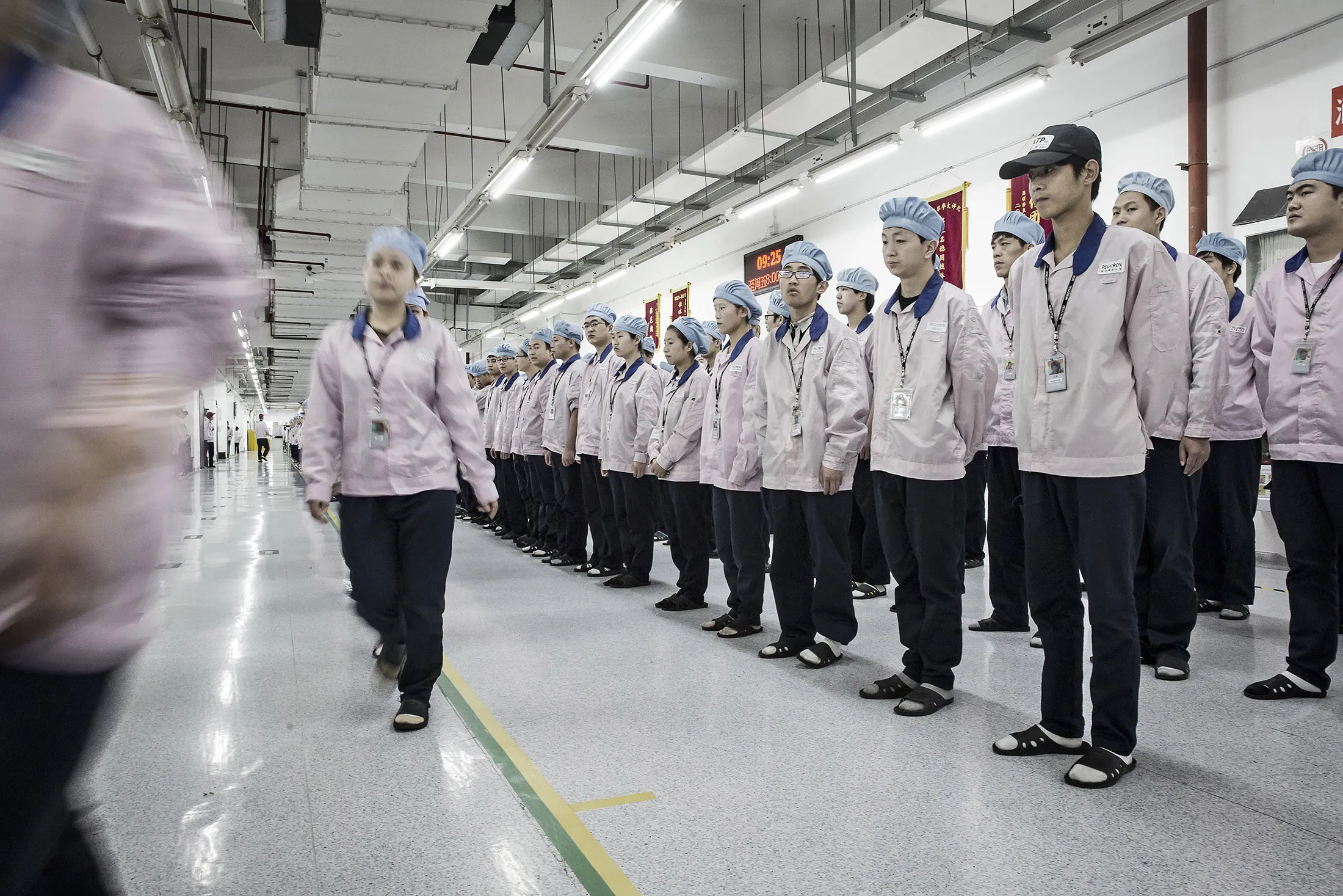Employees make their way to the assembly line area after lining up for roll call at a Pegatron Corp. factory in Shanghai, China, on Friday, April 15, 2016. This is the realm in which the world's most profitable smartphones are made, part of Apple Inc.'s closely guarded supply chain.
