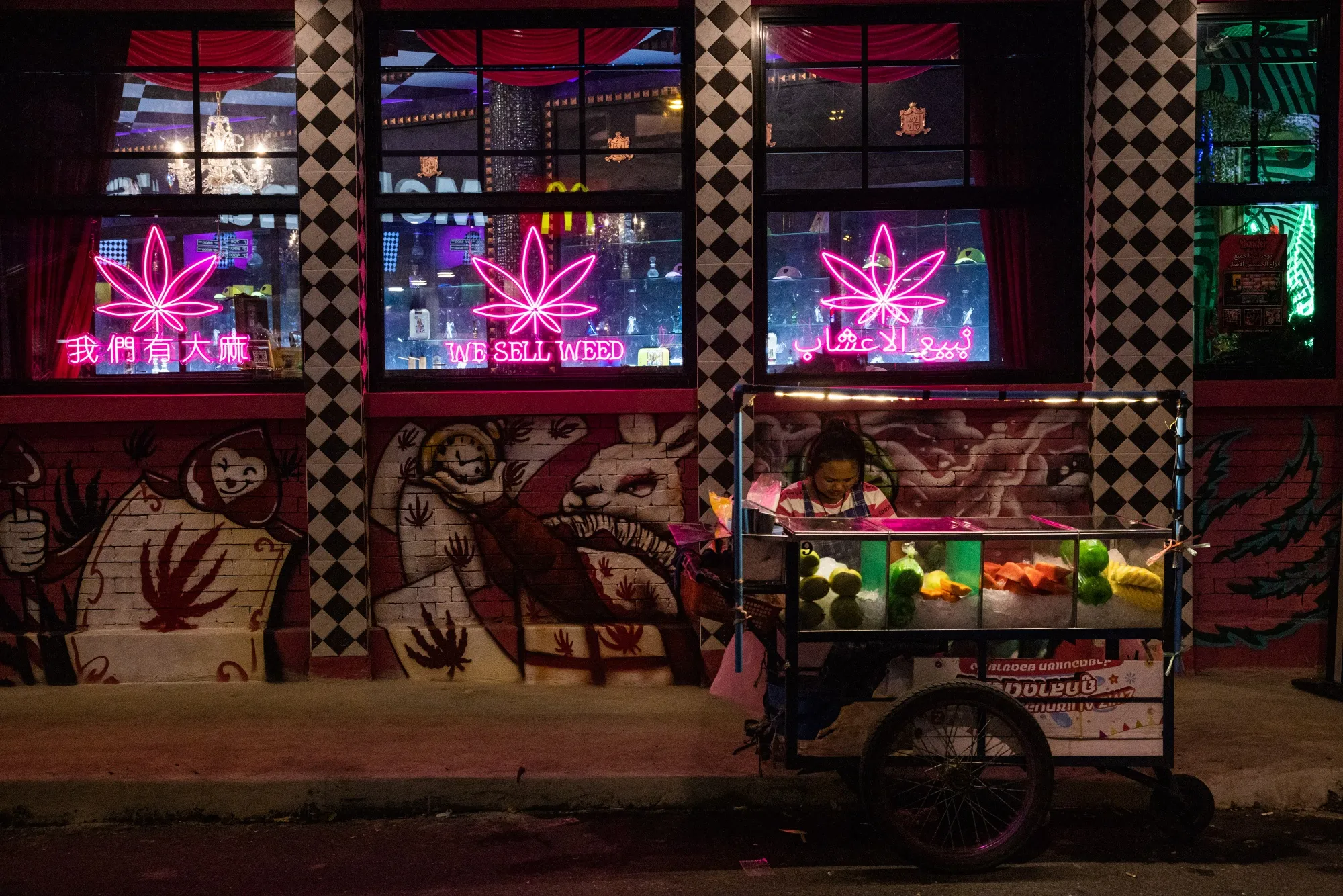 A street vendor sells sliced fruits outside the Wonderland marijuana dispensary in Bangkok, on Nov. 23.