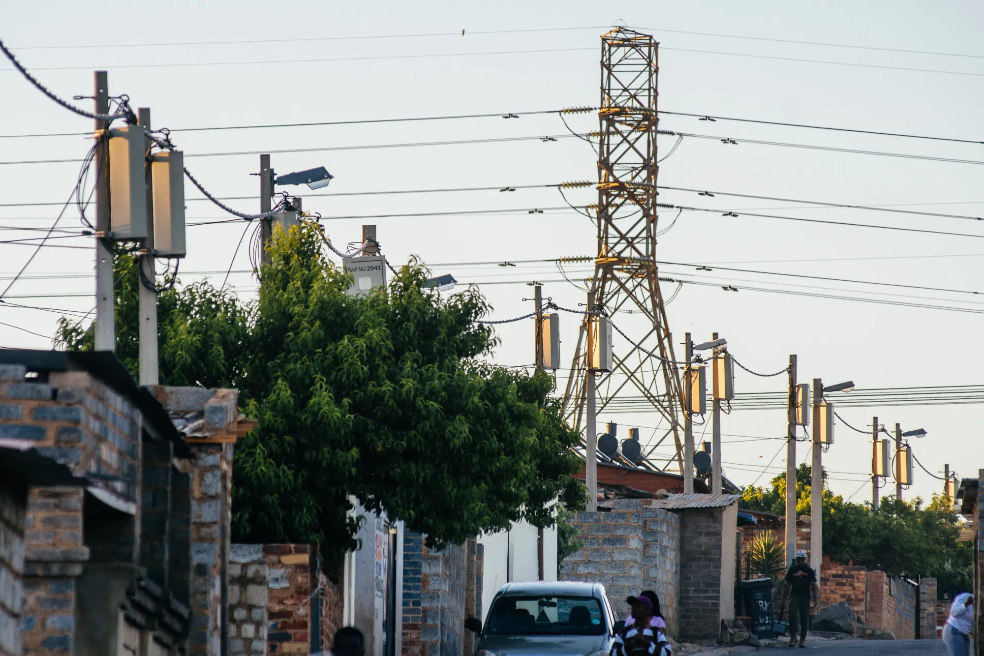 A pylon tower carries electrical power linesover residential shacks and electrical boxes in the Alexandra township outside Johannesburg, South Africa, on Thursday, Oct. 6, 2016. Eskom Holdings SOC Ltd. is building new electricity stations to end the power cuts that were imposed for about 100 days last year, curbing growth in Africa's most-industrialized nation.