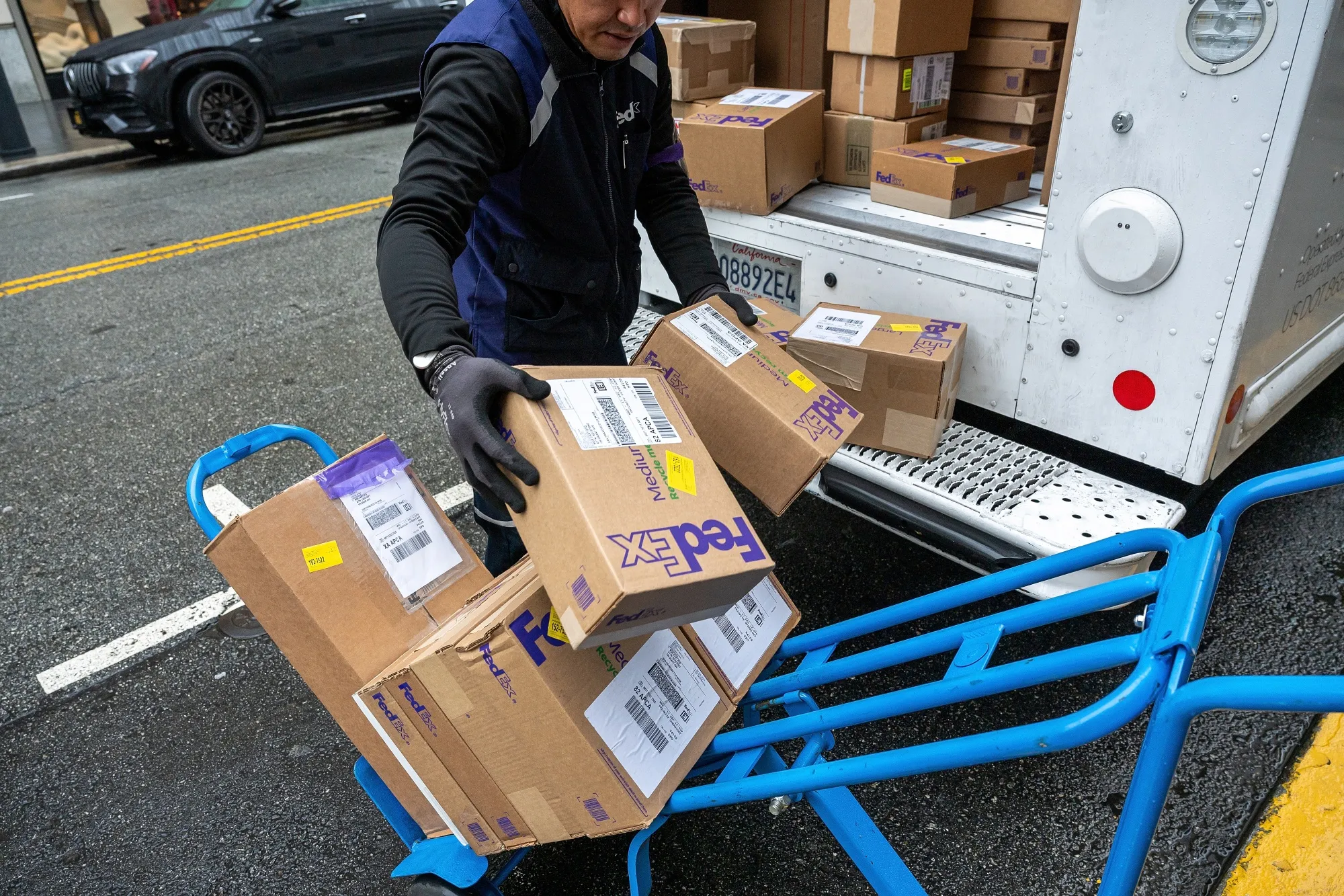 A worker unloads packages from a FedEx truck in San Francisco.