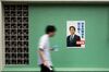 A man walks past a poster of Japan's prime minister, Shinzo Abe pasted to a green wall
