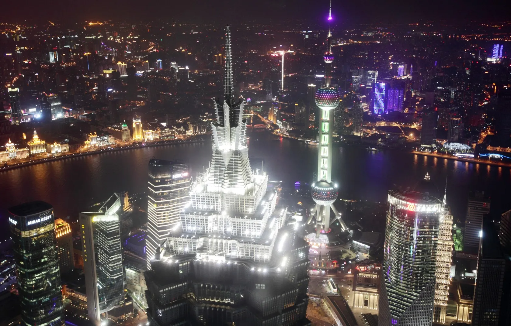 The Jin Mao Tower, center left, and the Oriental Pearl Tower, center right, stand among other commercial buildings as seen from the Shanghai World Financial Center at night in the Pudong area of Shanghai.