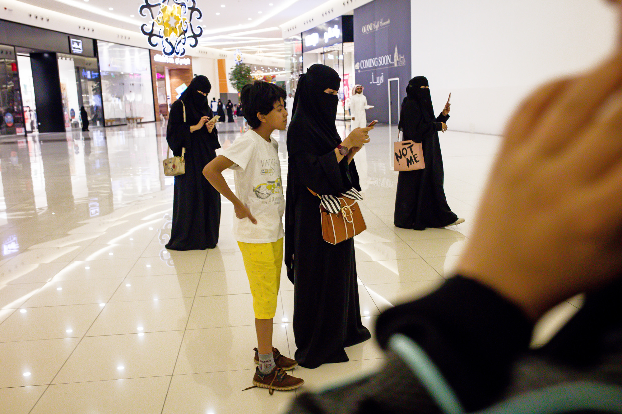 Women use their smartphones while visiting the Al Yasmin mall, operated by Arabian Centres, in Jeddah