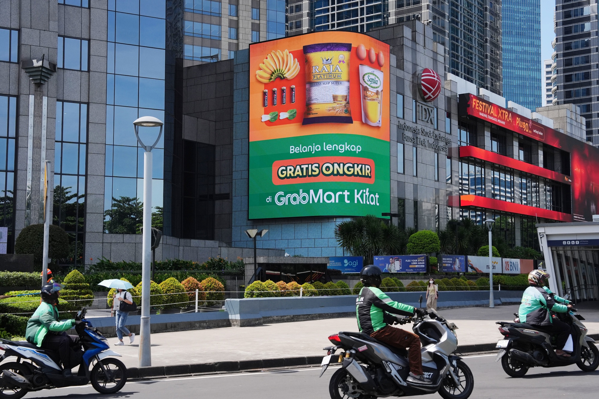 Gojek and Grab drivers ride past an advertisement for GrabMart in Jakarta, Indonesia, on Monday, Nov. 24, 2025. GoTo Group appointed a new chief executive officer, a move that’s expected to speed the takeover of Indonesia’s largest internet company by Grab Holdings Ltd. Photographer: Dimas Ardian/Bloomberg