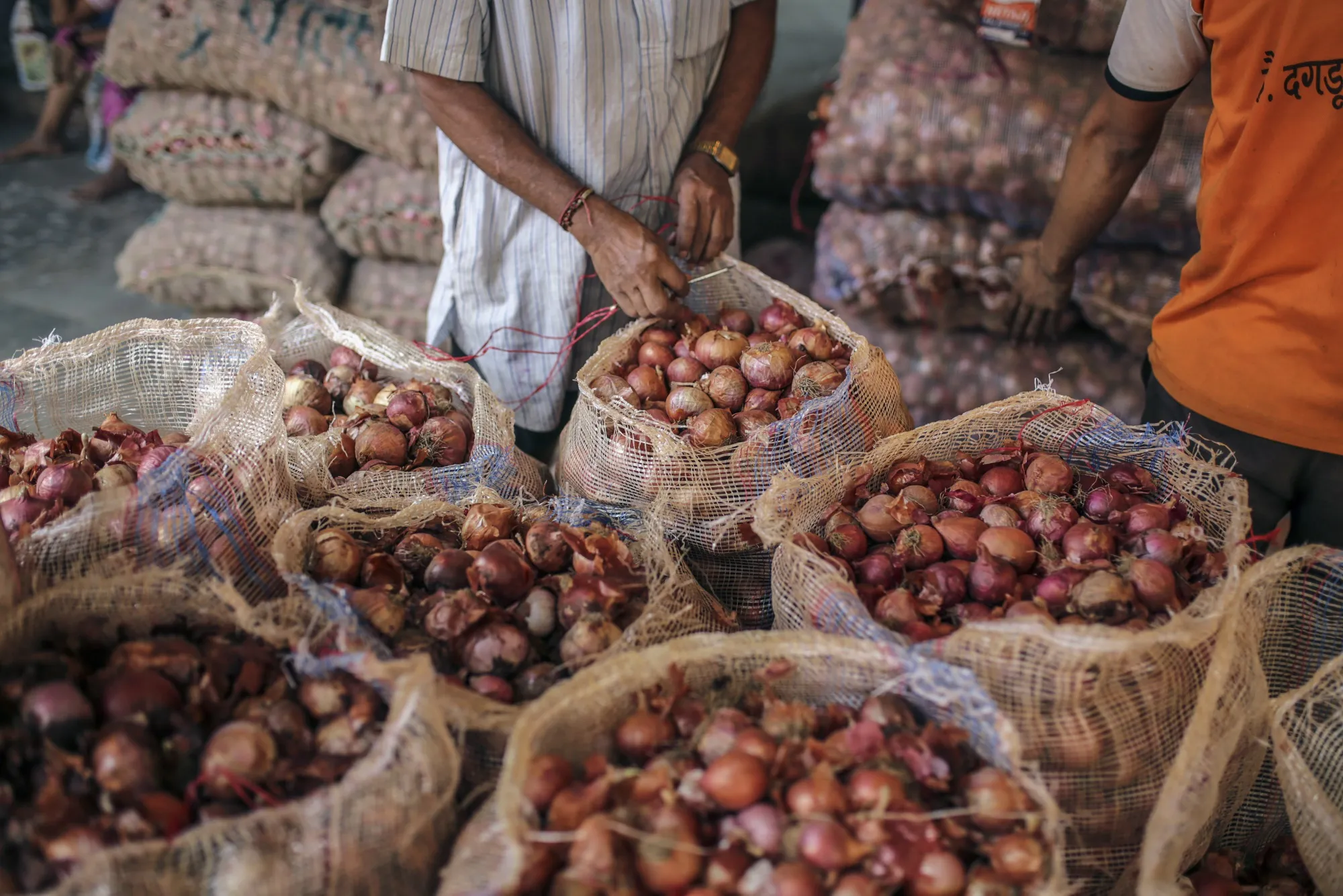A worker seals a sack of onions at a&nbsp;wholesale market in Mumbai, India.