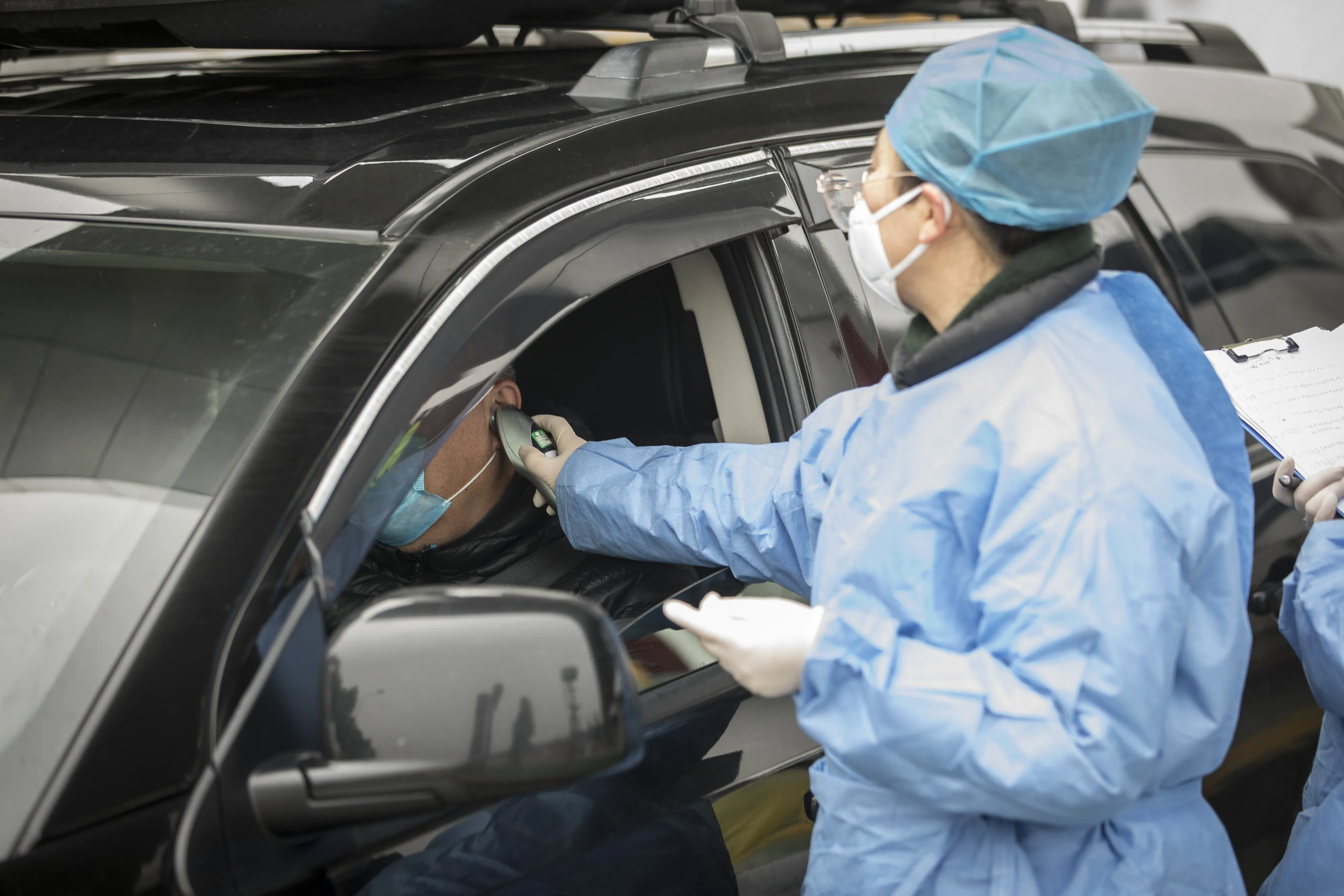 Health professionals check the temperature of a driver at a screening checkpoint&nbsp;on the outskirts of Shanghai on Jan. 28.