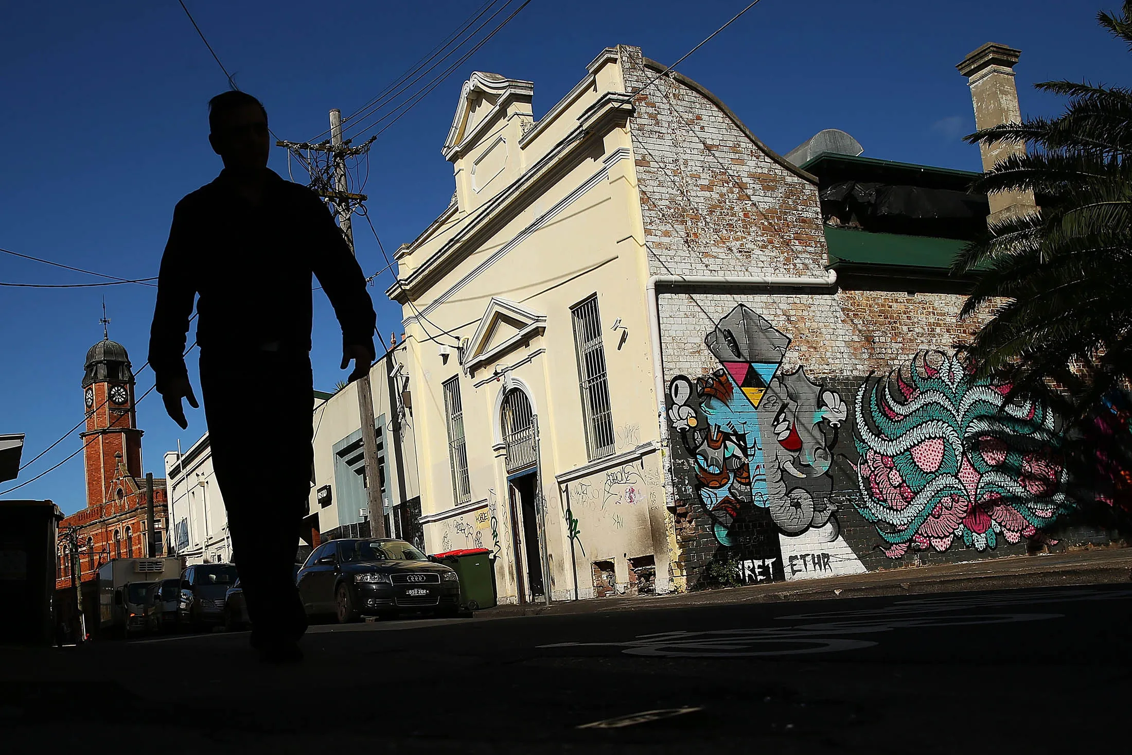 SYDNEY, AUSTRALIA - MAY 08: A man walks past properties strewn with graffiti on May 8, 2014 in Sydney, Australia. The Grafitti Control Amendment Act passed in the NSW legislative council yesterday includes tougher penalties a the ability for local courts to enforce community clean up duty on offenders.
