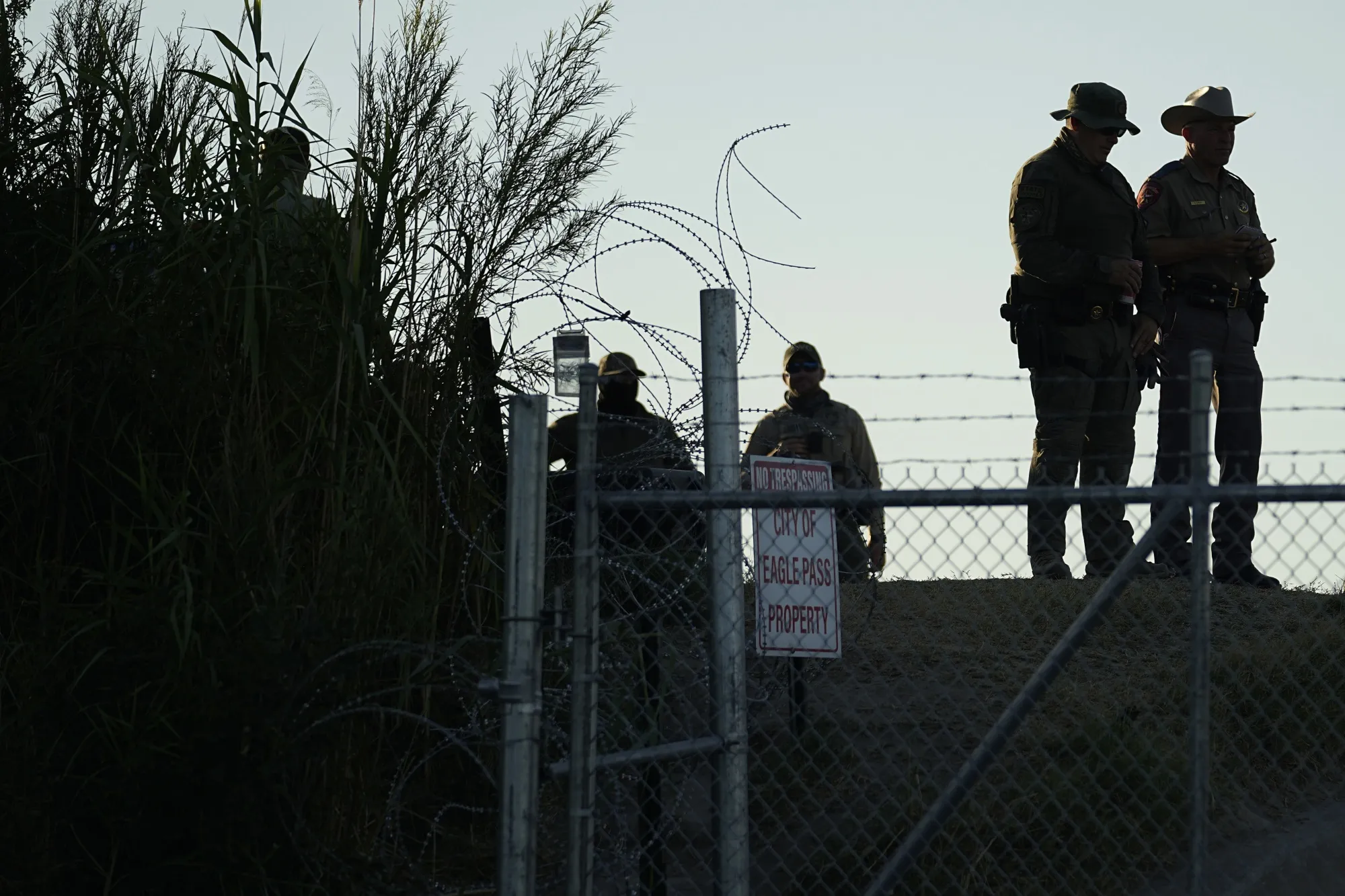 Texas troopers stand near a "No Trespassing" sign and concertina wire&nbsp;at Shelby Park on&nbsp;Aug. 1 in Eagle Pass, Texas.&nbsp;