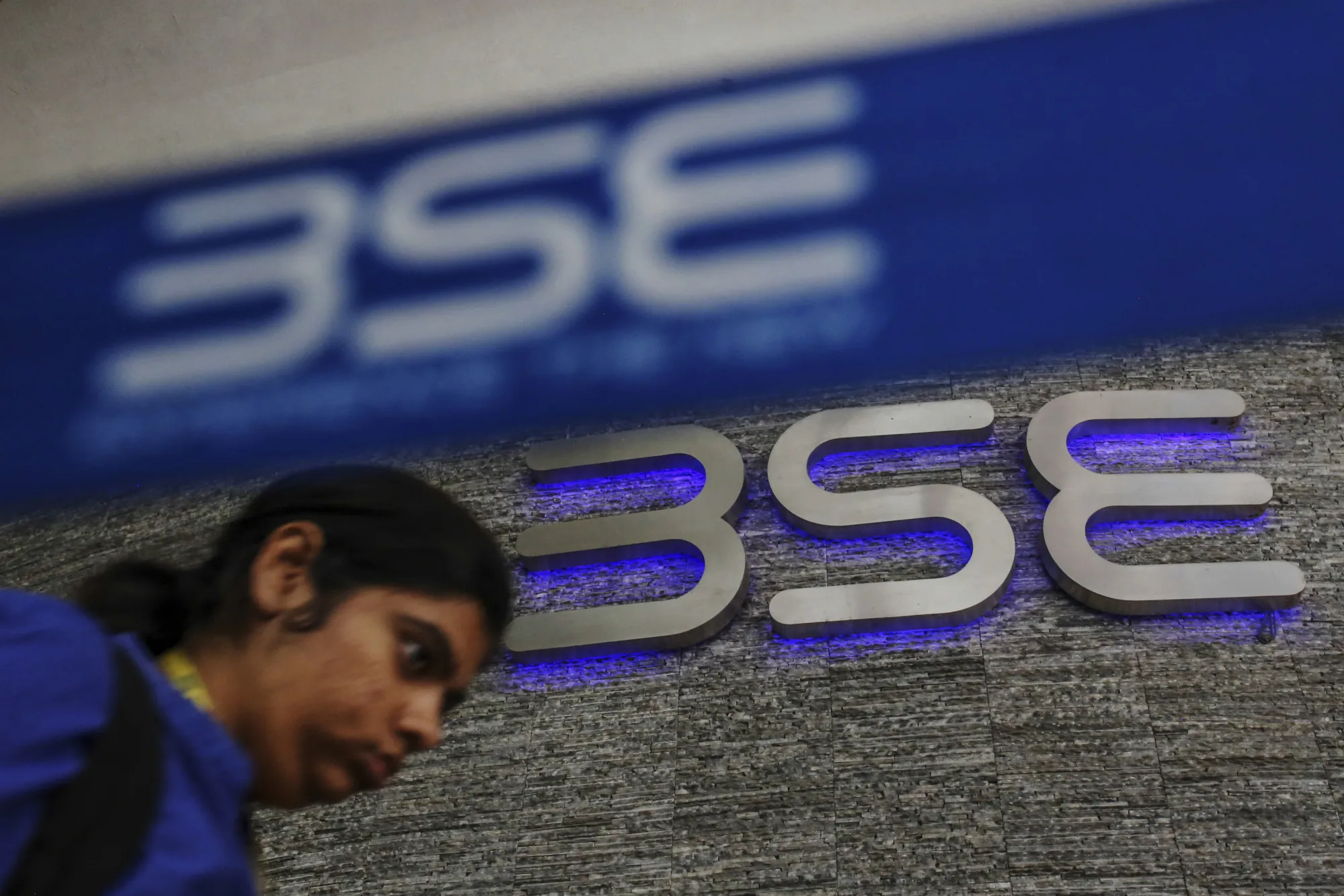 A man walks past the Bombay Stock Exchange (BSE) logo in Mumbai, India.