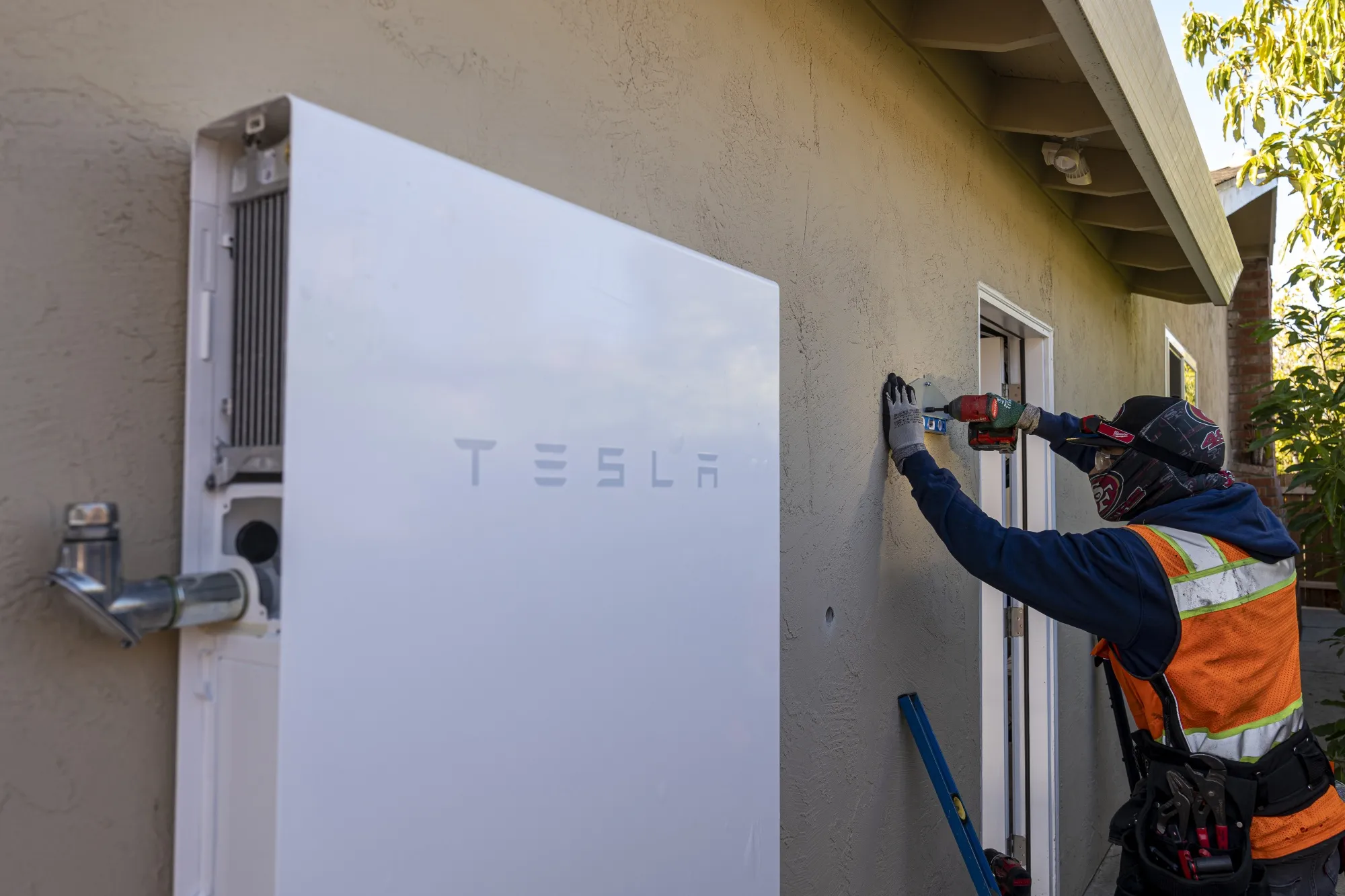A contractor installs hardware for a Tesla Powerwall battery unit at a home in San Jose, California.