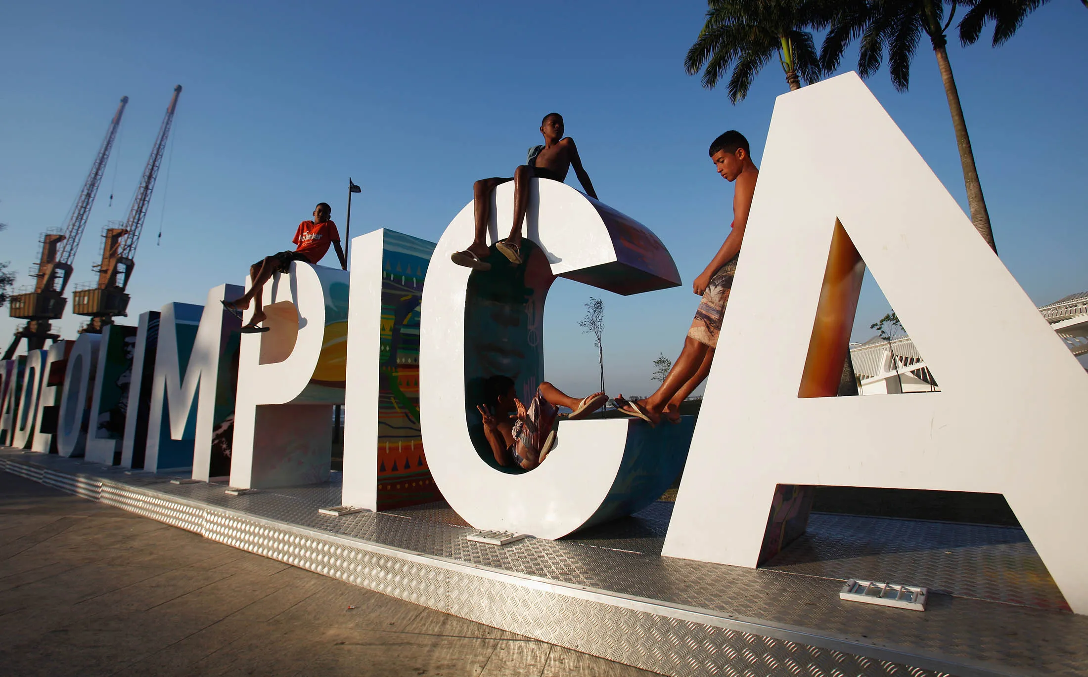 Teens sit on a new sign reading 'Cidade Olimpica,' or Olympic City, in Rio de Janeiro, Brazil.
