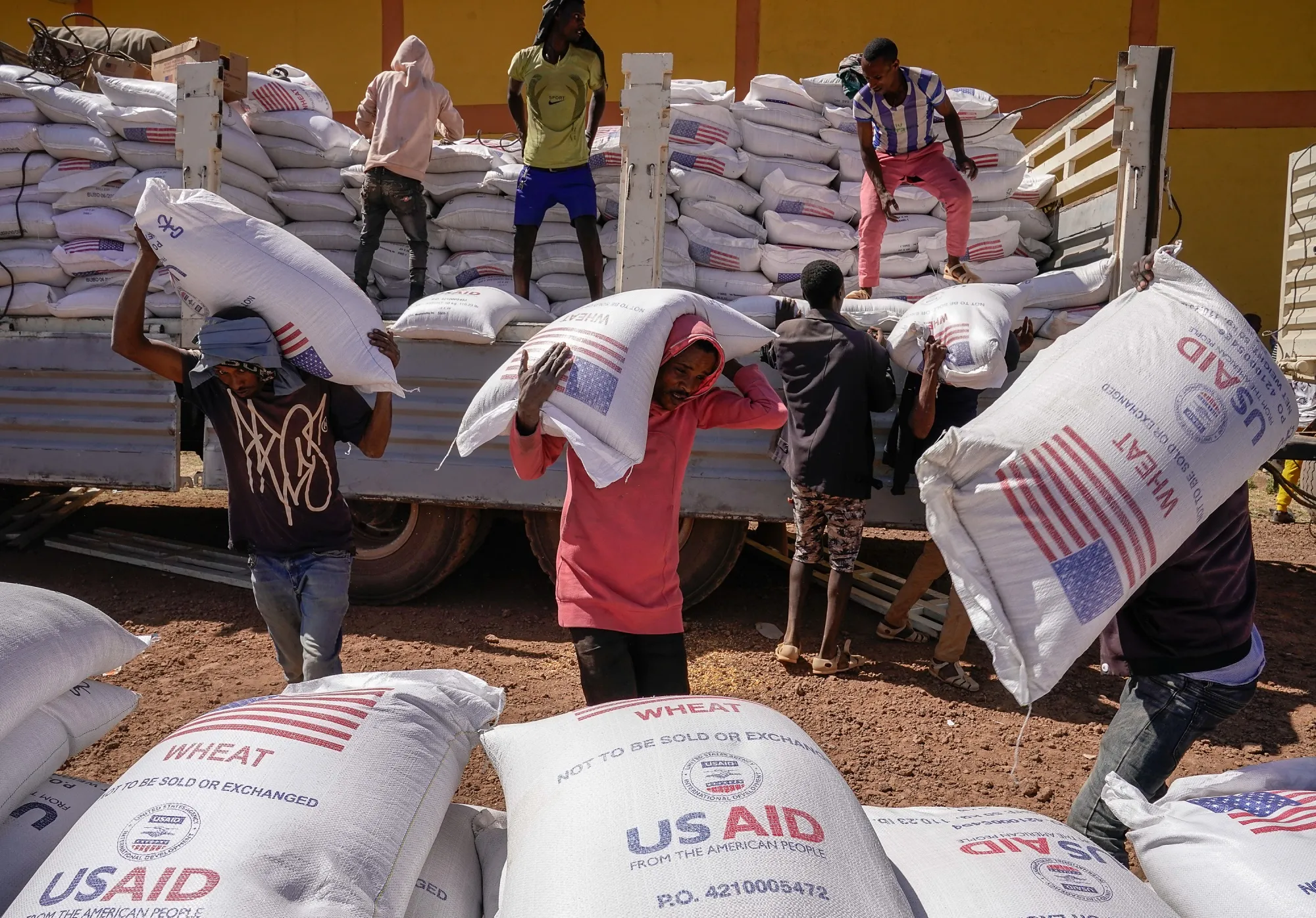 Volunteers unload sacks of wheat flour that were a part of an aid delivery from USAID in Ethiopia in 2021.