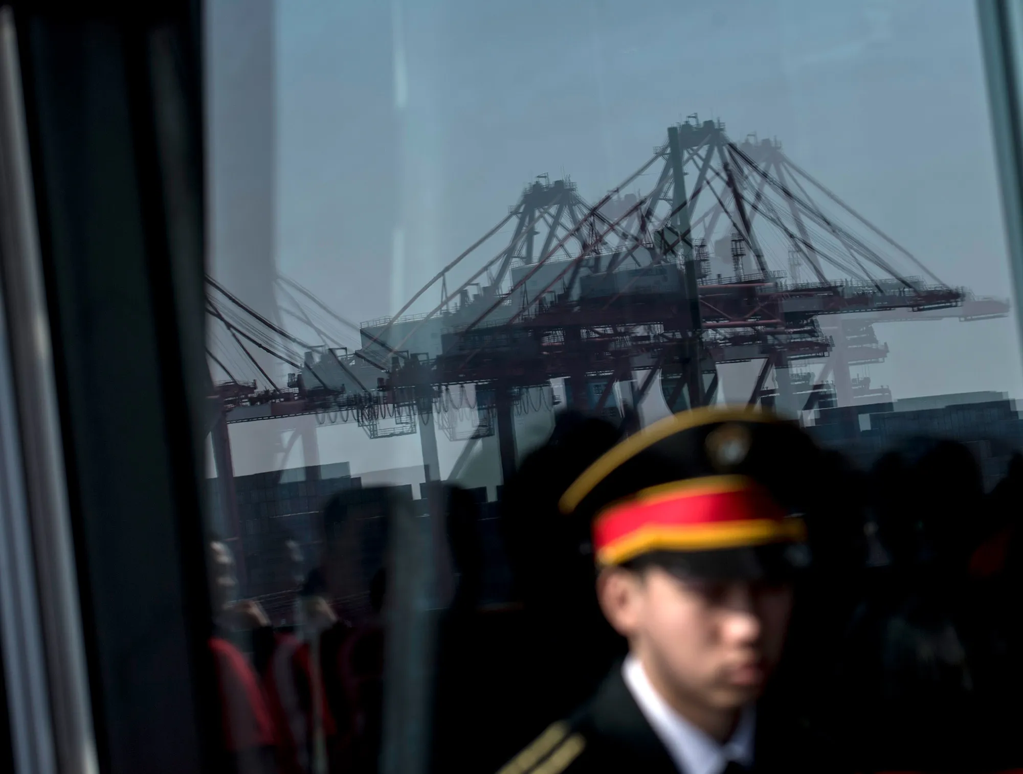 A security guard stands in front of a window reflecting the Yangshan Deep Water Port, part of the Shanghai.