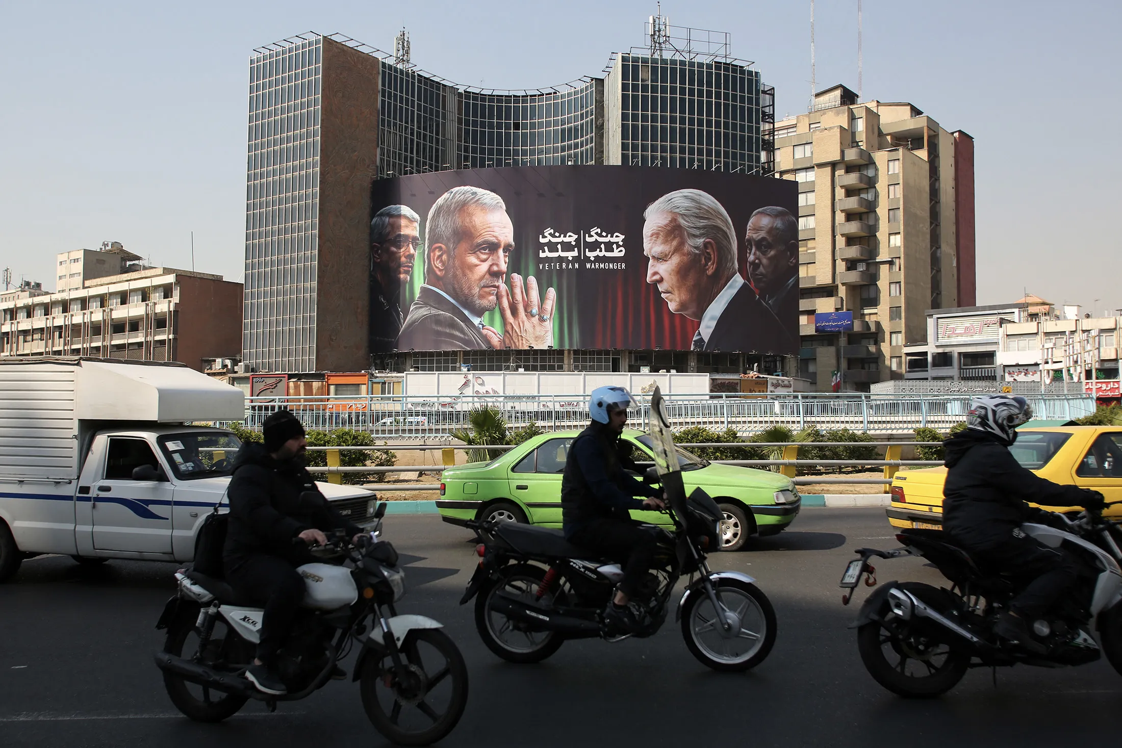 traffic passes a billboard featuring Masoud Pezeshkian&nbsp;and President Joe Biden, in Tehran, on Oct. 27.