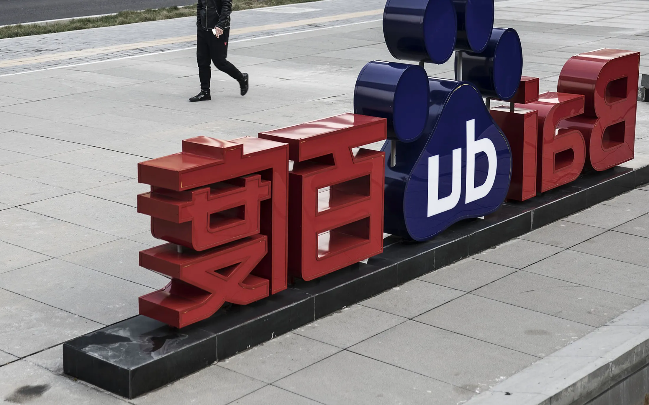 A man walks past a sign for Baidu Inc. at the entrance to the Baidu Technology Park in Beijing.
