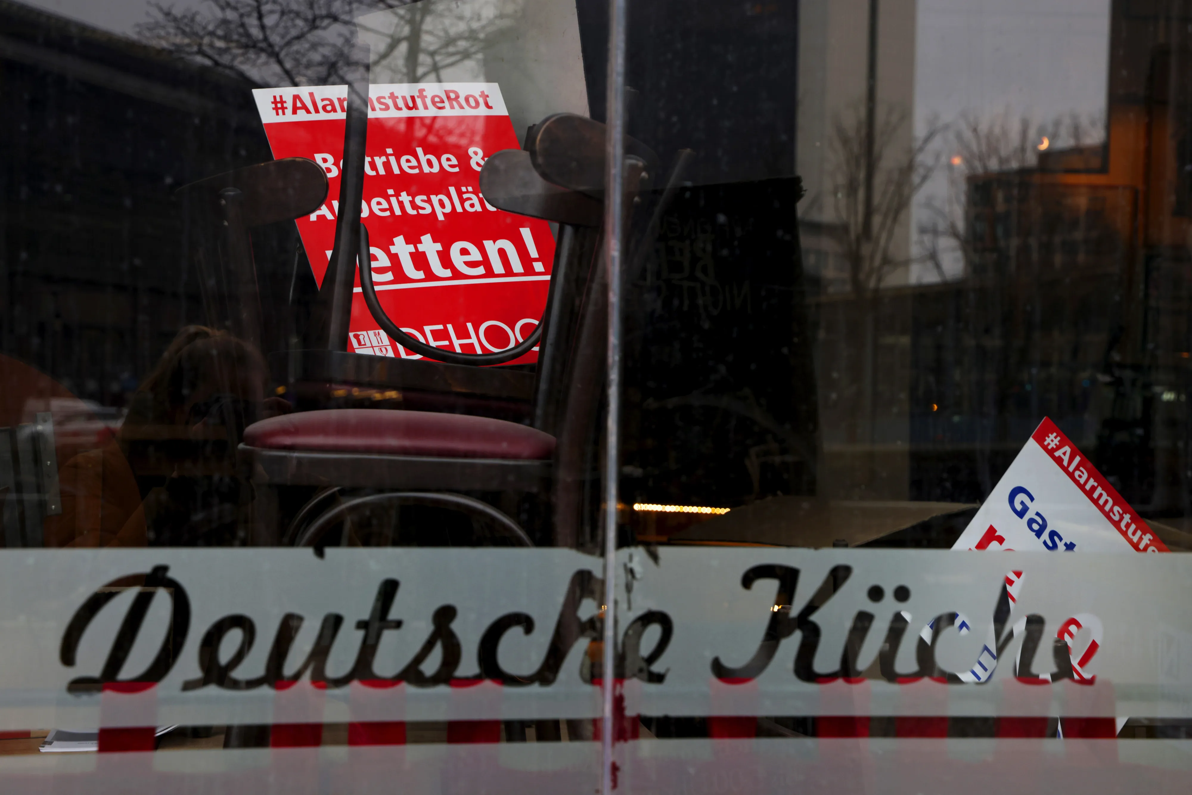 A sign reading 'business and workplace rescue' inside a closed restaurant in Berlin.