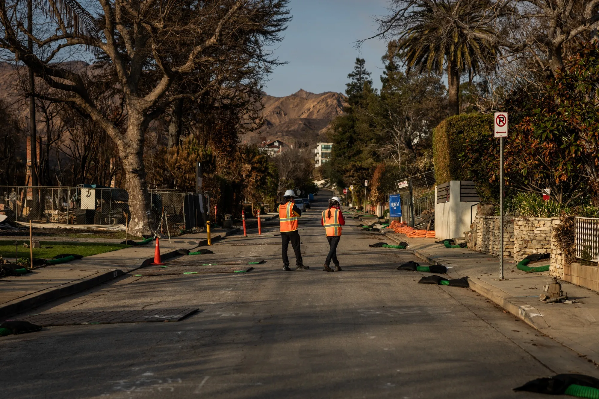 Workers examine homes after the Palisades Fire.