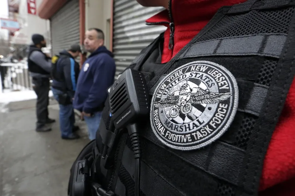 Immigration and Customs Enforcement officers and Federal Marshals try to gain entry to an apartment building in New York in pursuit of a suspect.