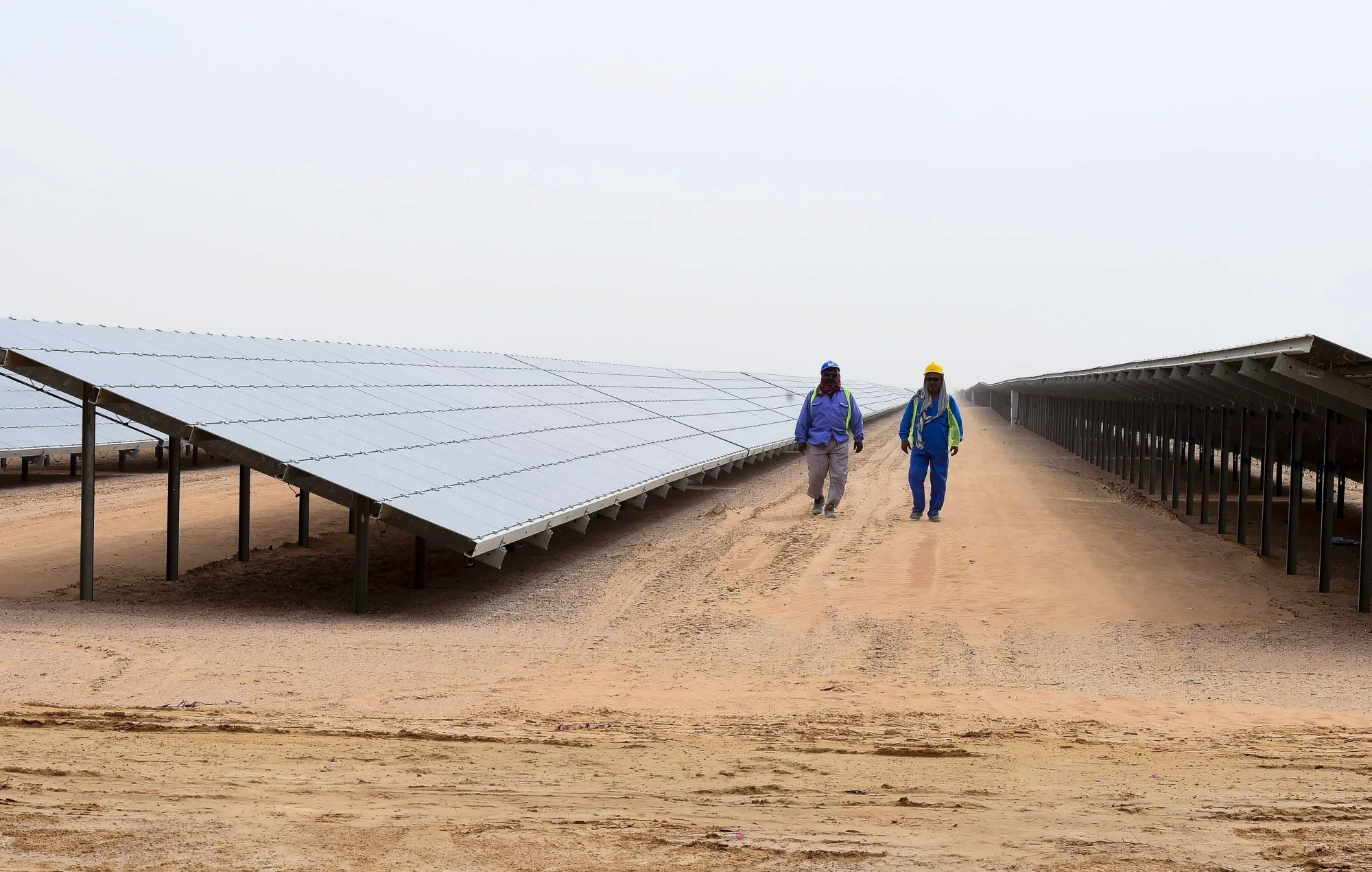 Employees walk past solar panels at the Mohammed bin Rashid Al-Maktoum Solar Park&nbsp;in Dubai.