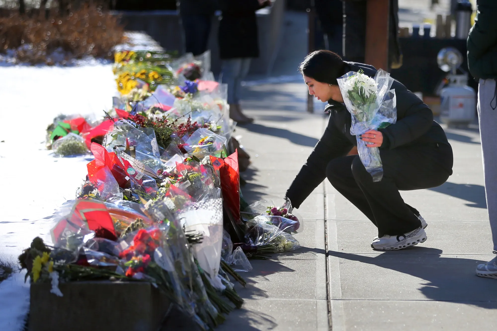 People place flowers at a memorial for shooting victims on the campus of Brown University in Providence, Rhode Island on Dec. 16, 2025.