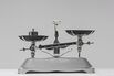 Old-fashioned weight on weighing scale against gray background