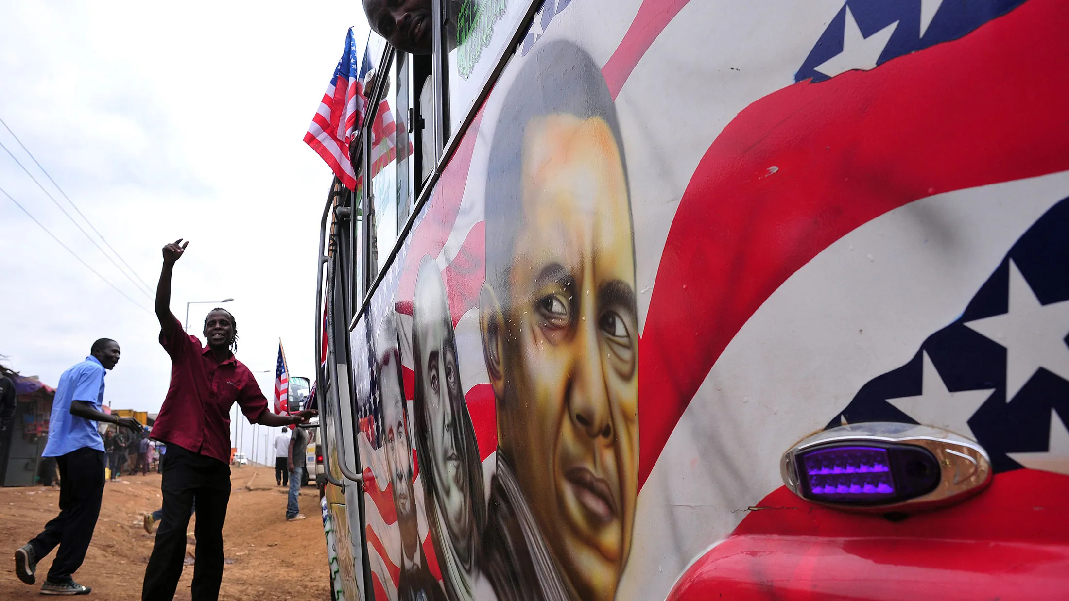 Solomon Murimia, a "matatu" minibus driver, gestures as he calls on clients beside his minibus with a painting depicting U.S. Presidents Abraham Lincoln and Barack Obama, as well as Benjamin Franklin, on July 22, 2015 in Nairobi.
