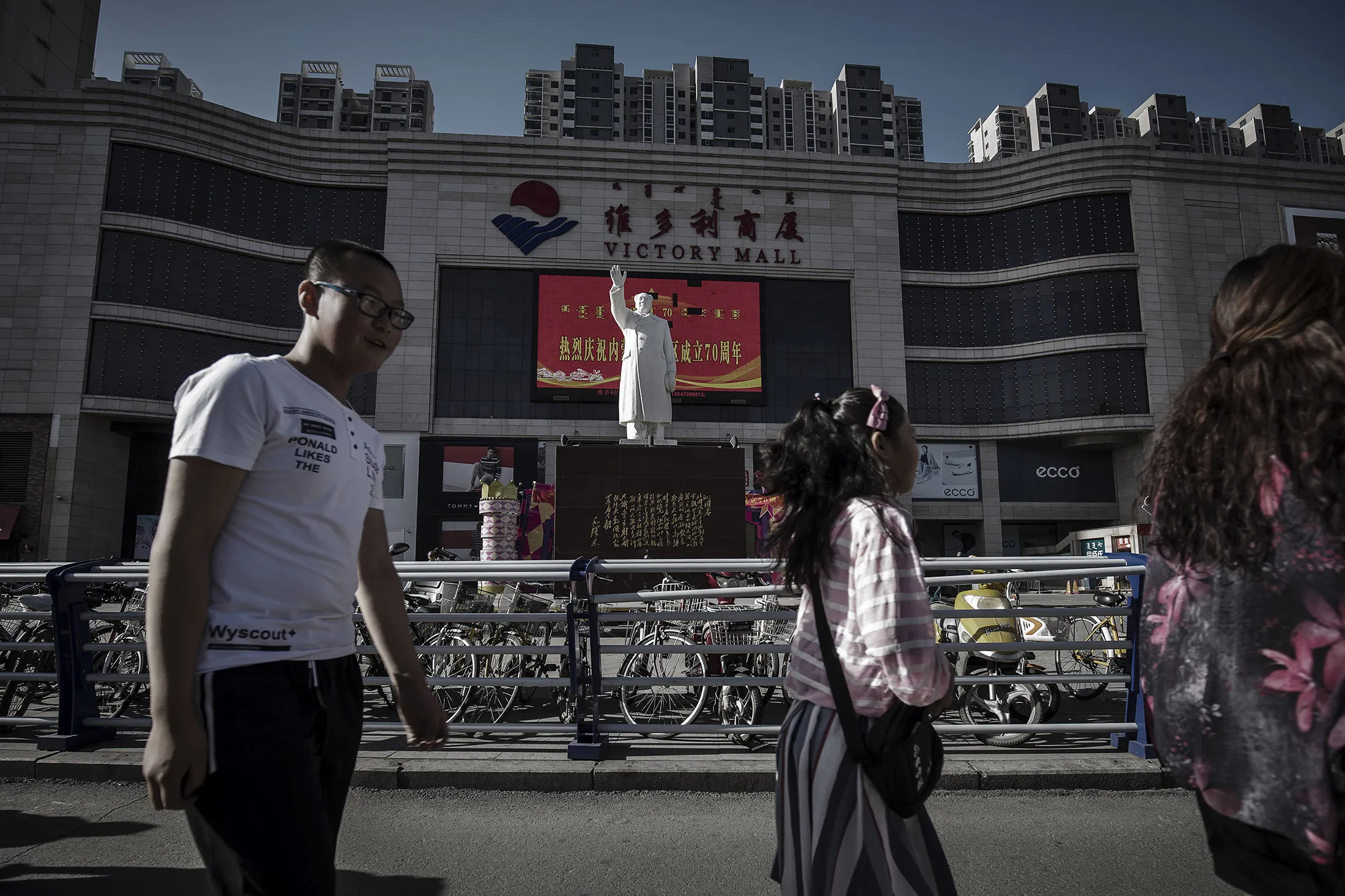Pedestrians walk past a statue of Mao Zedong displayed in front of the Baotou Victory Shopping Mall in Baotou, Inner Mongolia, China, on Friday, Aug. 11, 2017. China's economy showed further signs of entering a second-half slowdown, as curbs on property, excess borrowing and industrial overcapacity began to bite.
