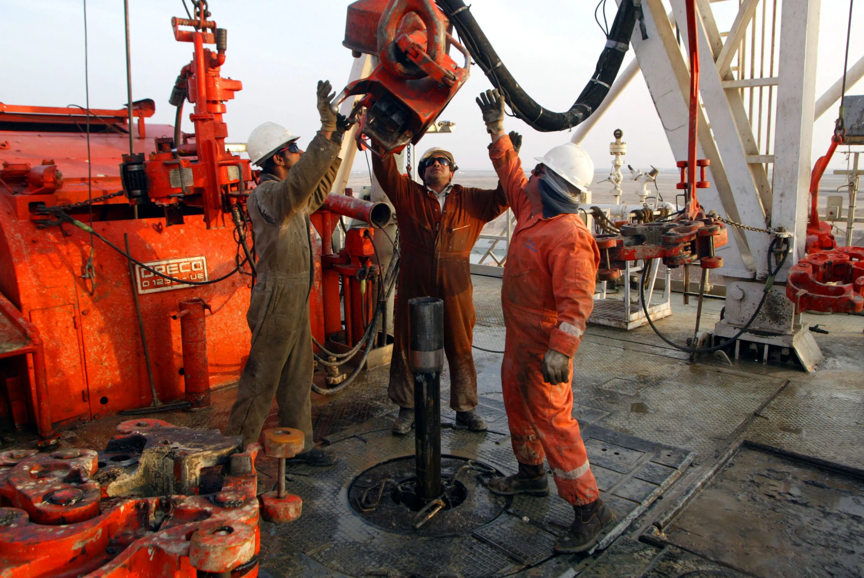 Kuwait Oil Company workers change pipes on a drilling rig.
