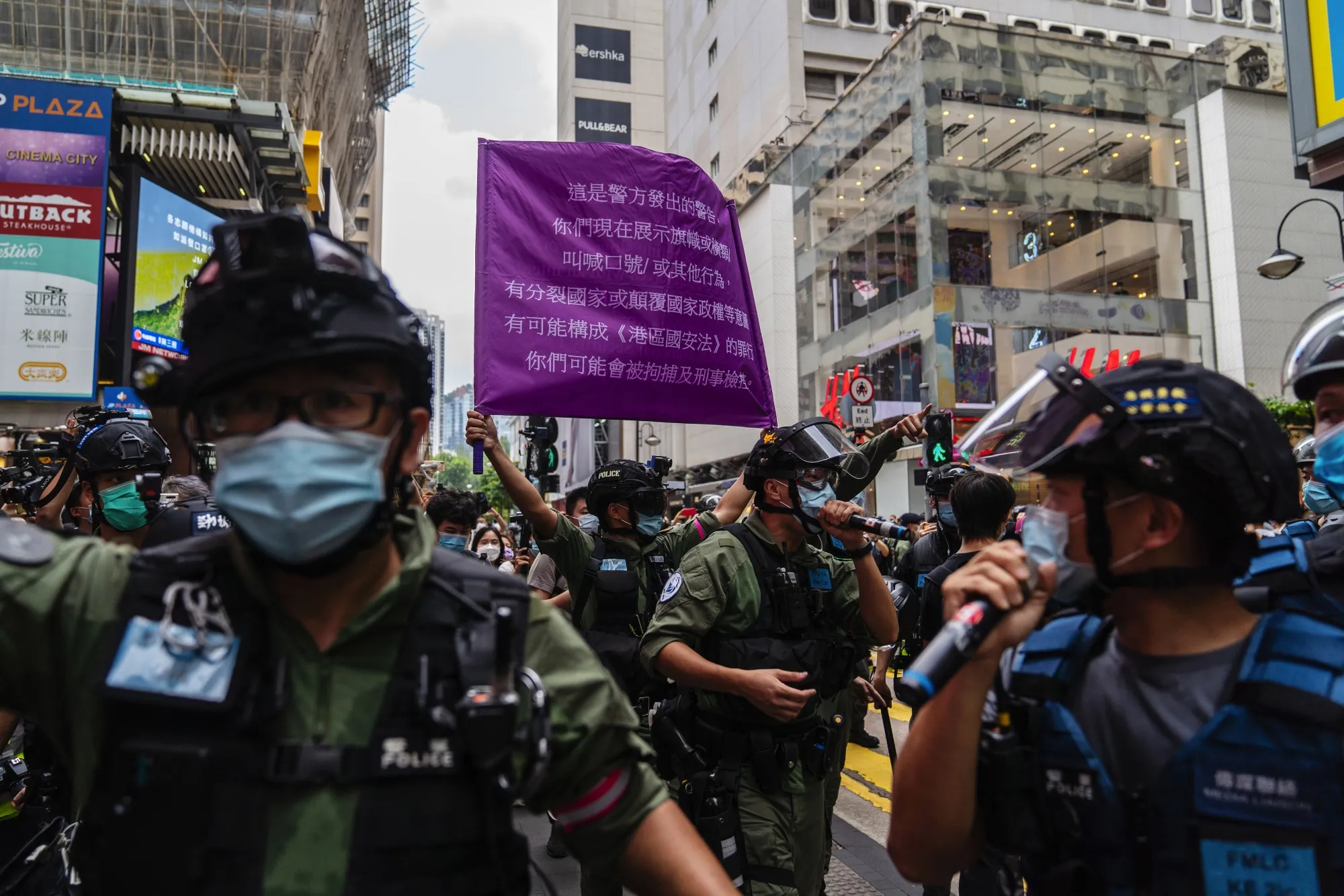 Riot police raise a flag warning protesters of actions that violate the new national security law, during a protest on National Day in Hong Kong, Oct. 1.